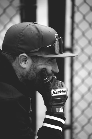 Man wearing a cap and sports gloves in profile.