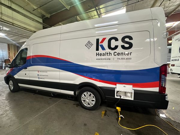A KCS Health Center van parked indoors with colorful stripes.