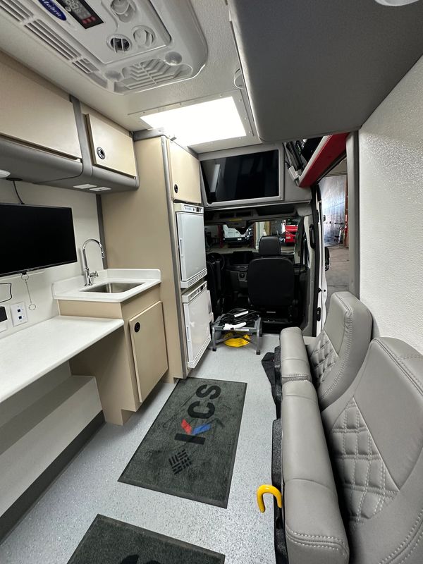 Interior of a compact, modern camper van with kitchen and seating area.