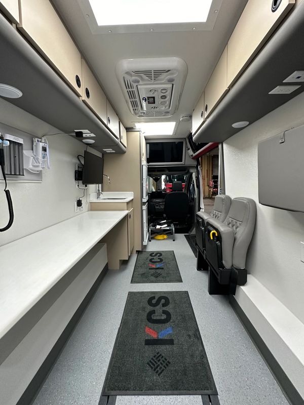 Interior of a modern medical or service van with organized cabinetry and seating.