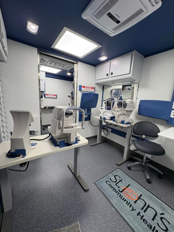 Modern optometry room with eye examination equipment and seating.