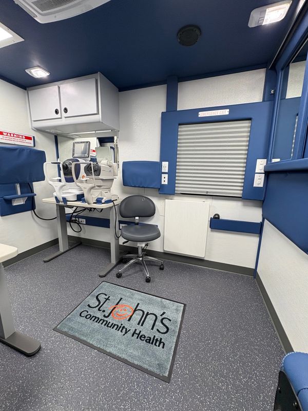 Interior of a medical exam room with diagnostic equipment and chair.