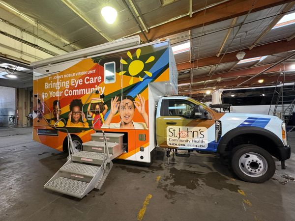 Mobile eye care unit truck parked indoors with colorful graphics.