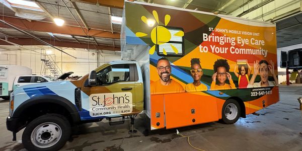 Mobile eye care unit truck with vibrant community health advertisement inside a warehouse.