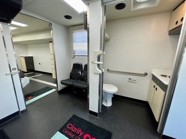 Interior of a mobile medical unit with seating and a restroom.