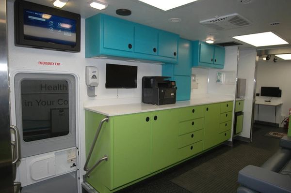 Interior of a mobile health clinic with colorful cabinets and medical equipment.