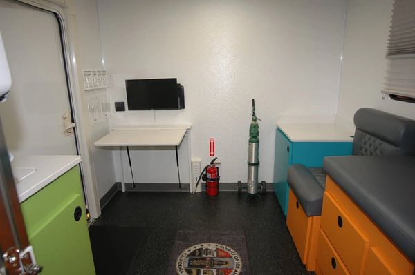 Interior of a clean, organized medical or emergency vehicle with seating and equipment.