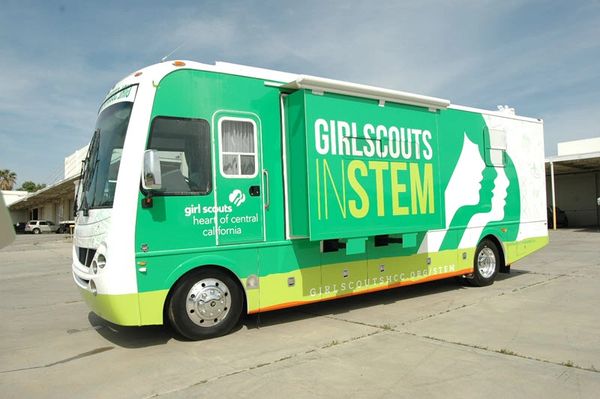 A green and white Girl Scouts STEM mobile unit parked outdoors.