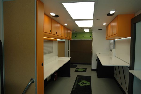 Interior of a mobile workspace with orange cabinets and bright lighting.