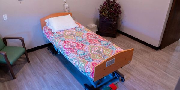 Single bed with colorful bedding in a simple room.
