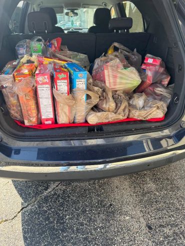 Car trunk full of grocery bags and boxes.