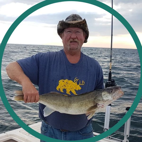 Man holding a large fish on a boat with ocean background.