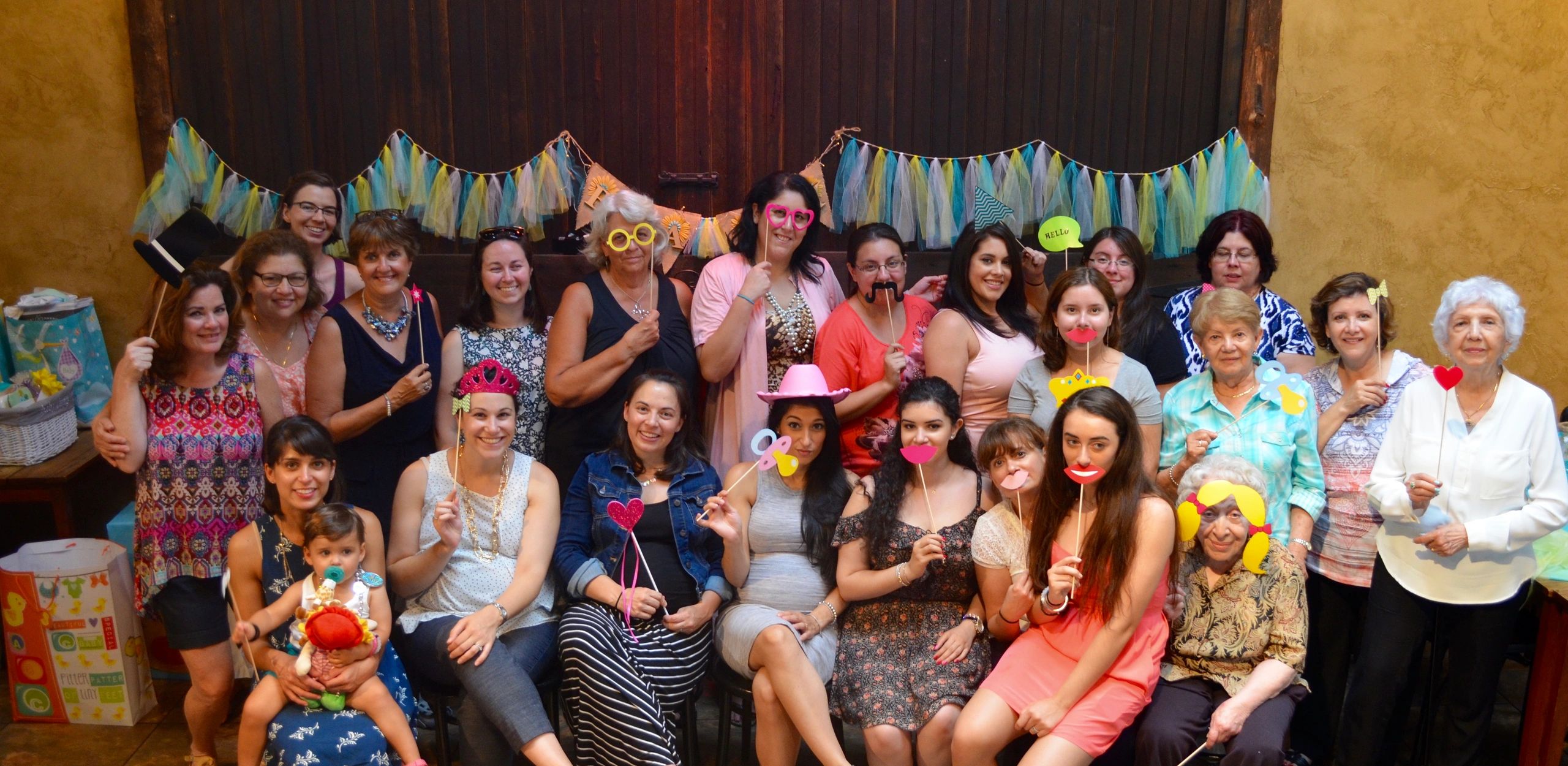 Group of women and a baby at a party with playful photo props.