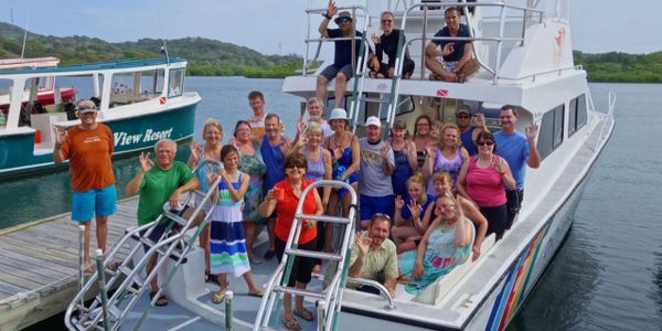 Group of happy people on a boat waving at the camera.