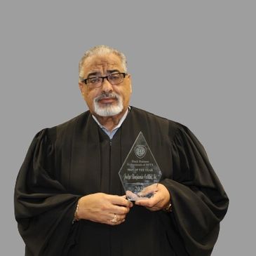 Man in judicial robe holding an award.