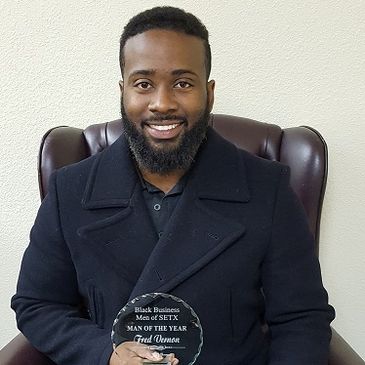 Man holding a 'Man of the Year' award, smiling.