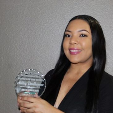 Woman holding a clear award plaque, smiling at the camera.