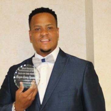 Man in suit holding an award plaque.