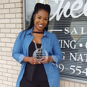 Woman smiling and holding a glass award in front of a salon.