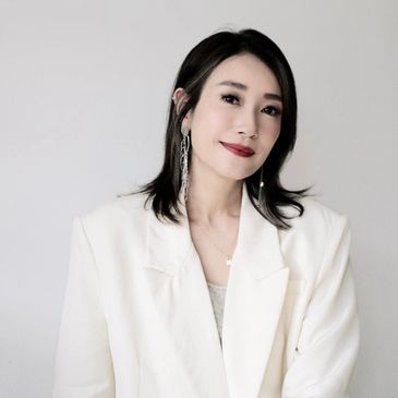 Woman with shoulder-length hair in a white blazer smiles softly.