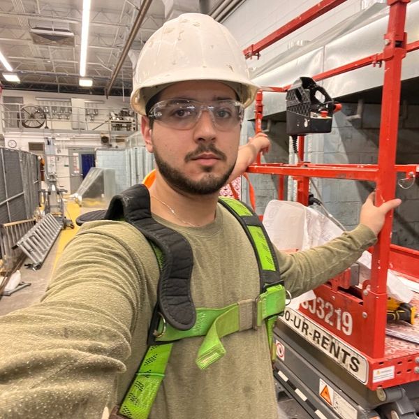 Worker in safety gear posing in an industrial setting.