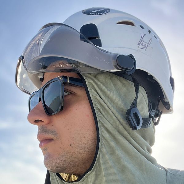 Man wearing a white safety helmet and sunglasses, looking focused.