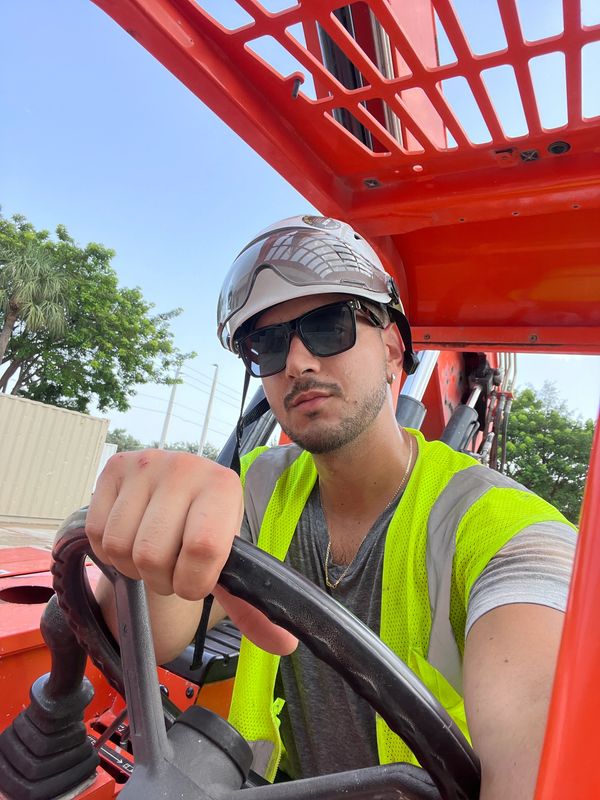 Construction worker in safety gear operating heavy machinery outdoors.