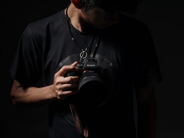 Person holding a camera against a dark background.