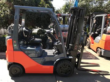 Orange Toyota forklift parked outdoors on a sunny day.
