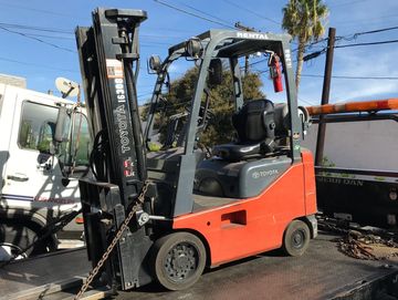 A Toyota forklift parked outdoors on a flatbed truck under a clear sky.