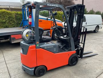 Orange and gray Toyota forklift parked outside with rental sign.
