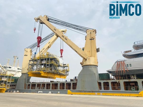 Large crane lifting heavy industrial equipment at a docked ship.