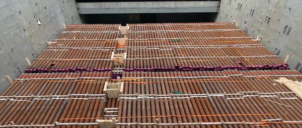 View of a construction site floor with evenly spaced wooden beams and concrete walls.