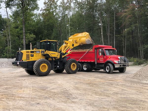 Loader loading dump truck with material