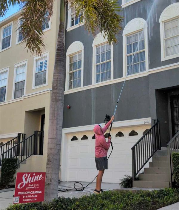 Shine pressure washer technician power washing and window cleaning a three story building.