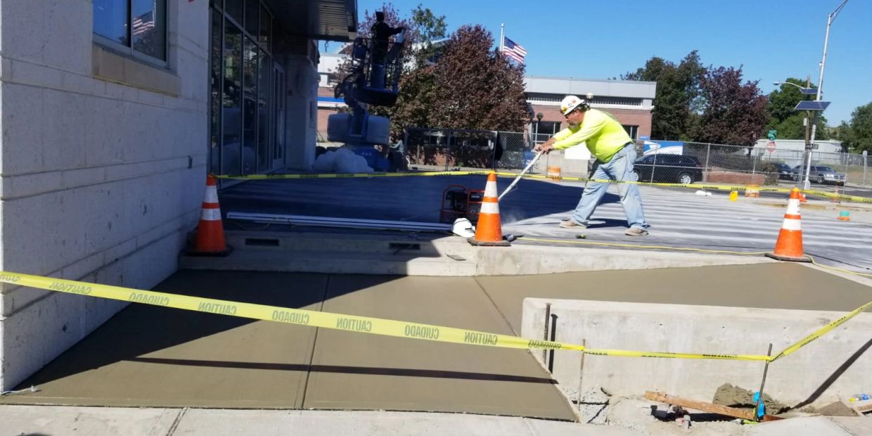 Worker smoothing fresh concrete at a construction site.