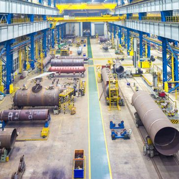 Large industrial workshop with heavy machinery and large cylindrical metal components.