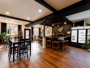 Bright and cozy brewery tasting room with wooden floors and black furniture.