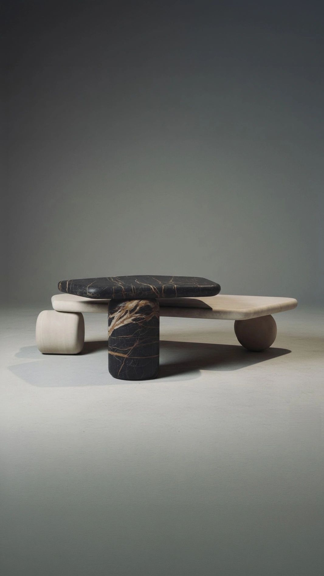 Modern sculptural coffee table with smooth stone surfaces and rounded legs.