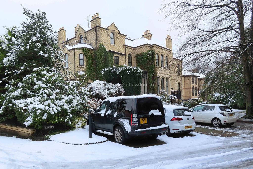 Winter view of old mansion house with cars parked in bays