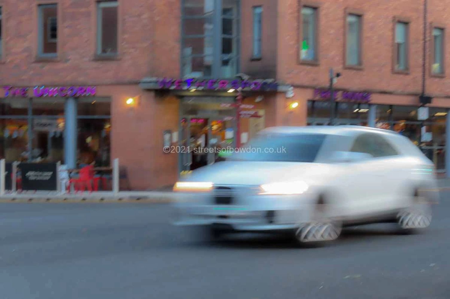 Blurred image of white car in front of pub