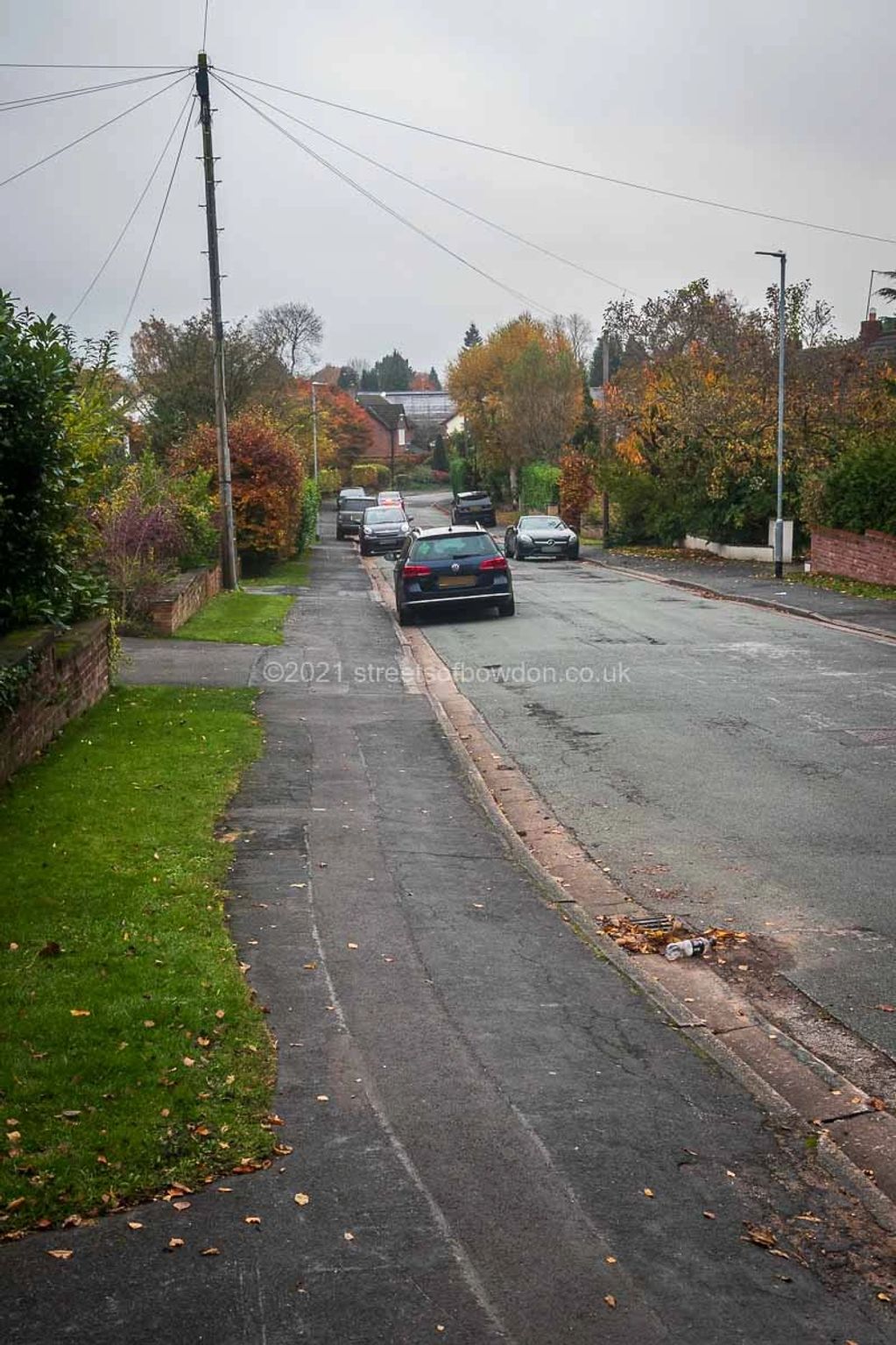 A cluster of parked cars on downhill slope 