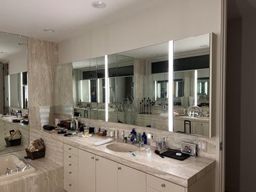 Modern bathroom with large mirrors and marble countertops.
