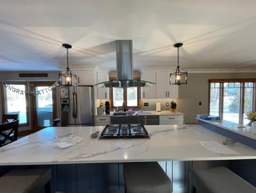 Modern kitchen with a large marble island and stainless steel appliances.
