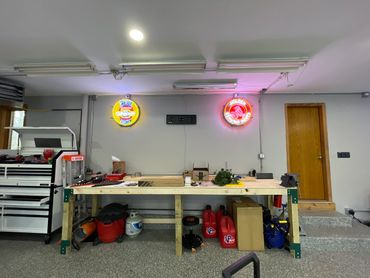 Organized garage workspace with tools and neon signs on the wall.