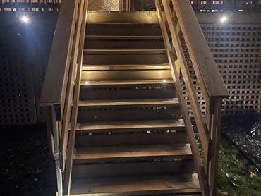 Wooden outdoor stairs illuminated with warm lights at night.