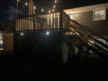 A backyard deck with string lights illuminated at night.