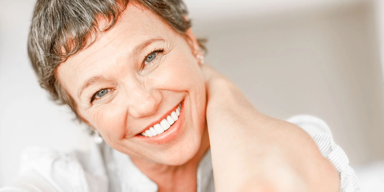 A smiling woman with short hair radiates confidence and wellness, symbolizing the empowerment and po