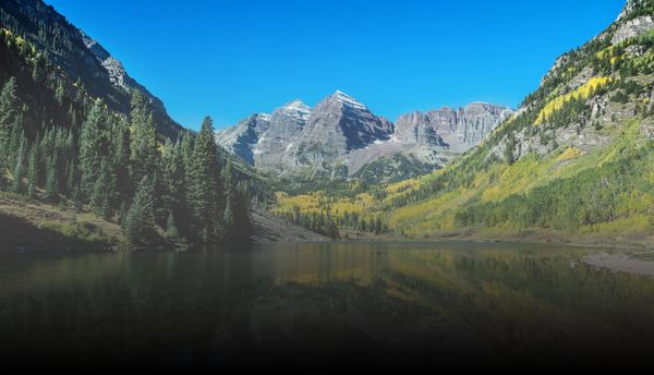 lake with blue sky and mountains with trees