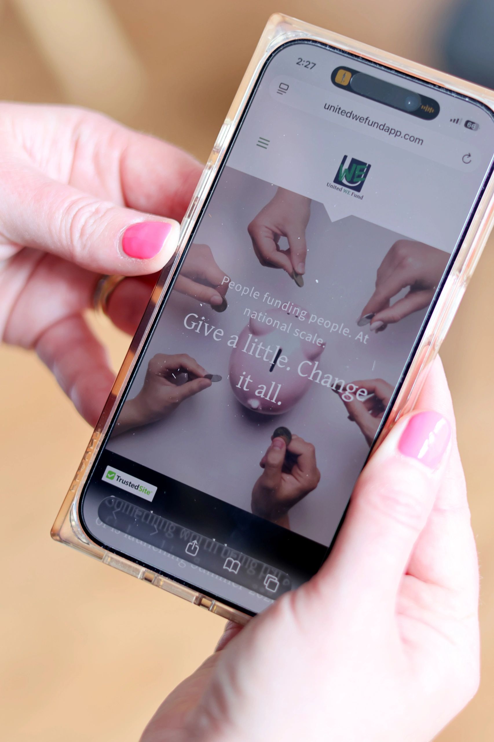 Person holding phone displaying United WE Fund donation webpage.